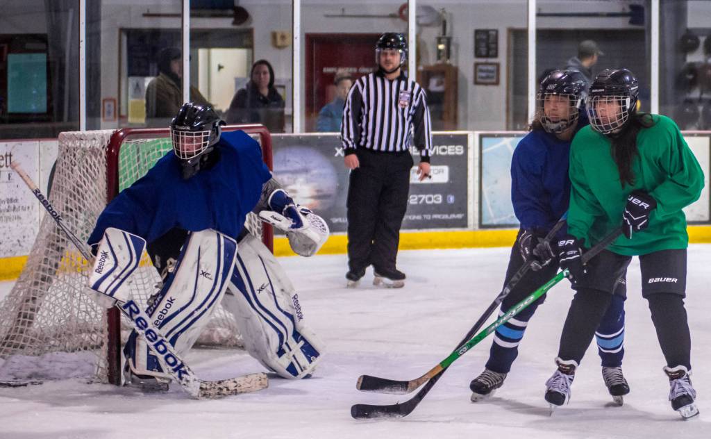 Val Martinez (blue) and Ry Akhund battle for position in front of Akhund&rsquo;s teammate goalie Jason Hort during last year&rsquo;s Juneau Jamboree at Treadwell Ice Arena. (Photo courtesy of Steve Quinn)
