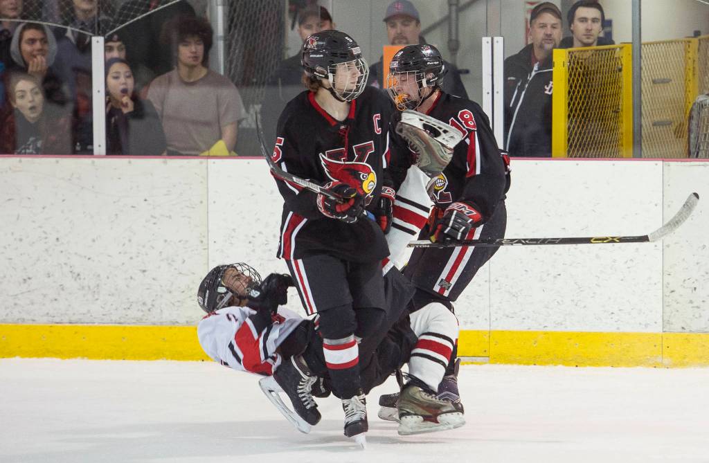 Juneau-Douglas&rsquo;s Blake Bixby is knocked down by Kenai&rsquo;s Jakeb O&rsquo;OBrian, right, in front of Kenai&rsquo;s Levi Mese at Treadwell Arena on Friday, Nov. 17, 2017. O&rsquo;Brian was called for roughing on the play. (Michael Penn | Juneau Empire)