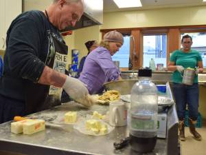 Father Gordon Blue, left, and Mary Alice McKeen, middle, prepare pie filling at a the Holy Trinity Church on Saturday. Blue and McKeen helped with the church&rsquo;s &ldquo;pie-a-thon&rdquo; charity event, where they made 300 pies for sale and for donation in preparation for Thanksgiving Day. (Kevin Gullufsen | Juneau Empire)