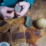 KC Mack shows his brand stamp he embosses on the leather of used baseball mitts he produces wallets from on Friday, Nov. 17, 2017. (Michael Penn | Juneau Empire)