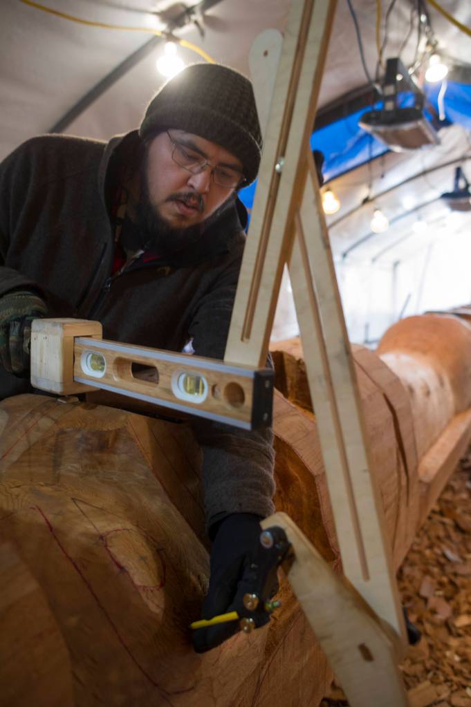 Herb Sheakley works on the Wolf Totem Pole at Harborview Elementary School on Tuesday, Dec. 5, 2017. (Michael Penn | Juneau Empire)