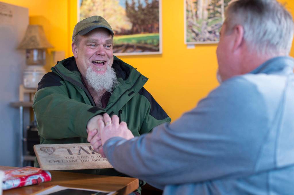 Russell Peterson, left, meets and thanks Guy Holt on Tuesday, Dec. 19, 2017, for returning a carved plaque Holt found 11 years ago at Sandy Beach. Peterson carved the plaque and left it at the gravesite of his dog, Taka. (Michael Penn | Juneau Empire)