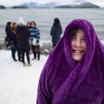 Maisy Messing, 10, stays warm in her robe as she wait for annual Polar Bear Dip at Auke Recreation beach on Monday, Jan. 1, 2018. (Michael Penn | Juneau Empire)