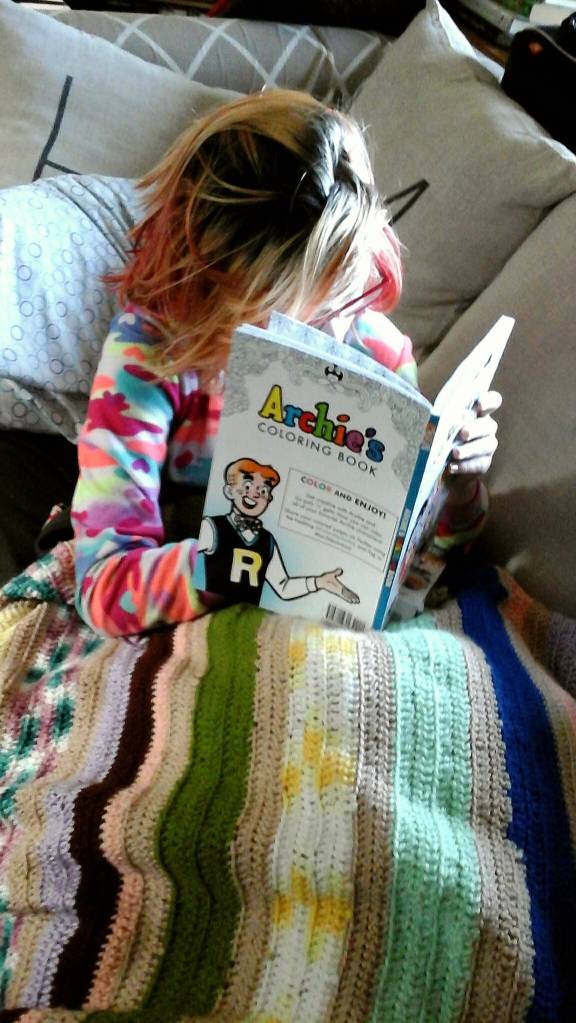 A. Darden curls up under an afghan as the temperature outside drops to the low twenties. She&rsquo;s transported to sunny Riverdale as she colors. Photo by Tara Neilson