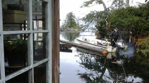 Gary Neilson tows the new log to put into place behind his floathouse. Photo by Tara Neilson