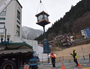 Tyler Blevins and Abe Ortega guide a clock on Front and Franklin streets as it&rsquo;s hoisted onto a truck for transportation. (Kevin Gullufsen | Juneau Empire)