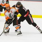 Juneau-Douglas High School&rsquo;s Dalton Hoy and West Anchorage&rsquo;s Chase Schwamm battle for the puck in the First National Cup state hockey championships. (Michael Dinneen | For the Juneau Empire)
