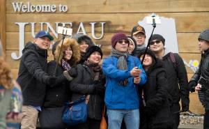 In this May 1, 2017 photo, tourists line up with their selfie sticks in front of the &ldquo;Welcome to Juneau&rdquo; sign after arriving by the first cruise ships of the season. (Michael Penn | Juneau Empire File)