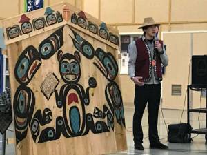 Local Yakutat Artist Daanak&rsquo;eesh Shane A. Brown talks to those in attendance at Riverbend Elementary during the unveiling of the &ldquo;house screen&rdquo; he designed and painted as a gift from Goldbelt Heritage Foundation to the school for its 20th anniversary Friday. (Gregory Philson | Juneau Empire)