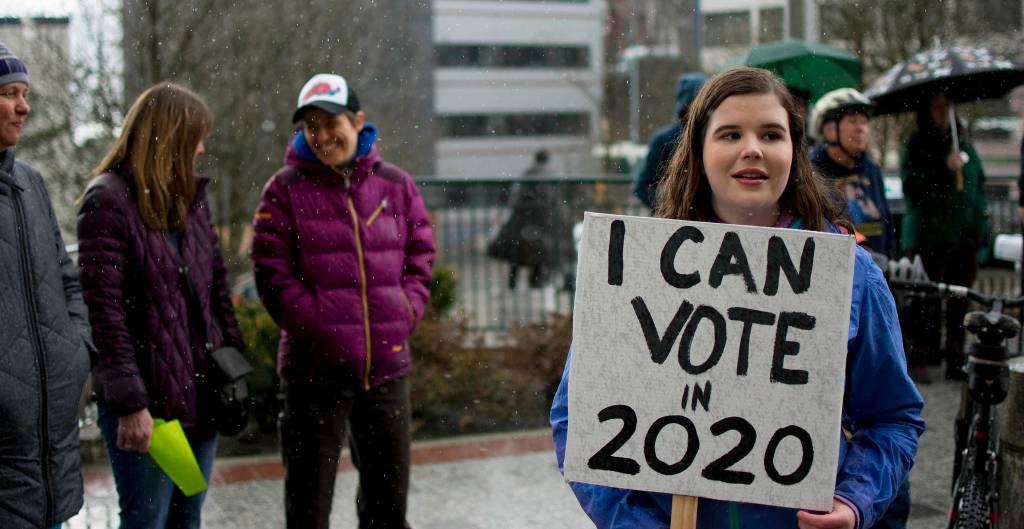 Stella Tallmon braves the rain to express her support for science and education in front of the Alaska Capitol on Saturday, April 14, 2018. (Richard McGrail | Juneau Empire)