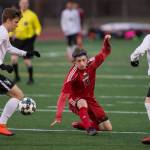 Juneau-Douglas&rsquo; Jackson Norberg punches the ball between West Anchorage&rsquo;s Dominic Owen, left, and Jack Nelson, right, at Adair-Kennedy Memorial Park on Friday, April 20, 2018. West won 3-1. (Michael Penn | Juneau Empire)