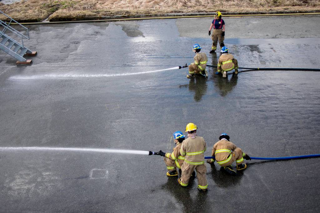 Capital City Fire/Rescue cadets work in teams and practice advancing hoses under pressure. Firefighter/EMT Krista Sheldon watches over them, giving instructions. (Richard McGrail | Juneau Empire)