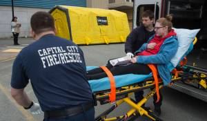 Capital City Fire/Rescue firefighter/EMTs Conner Hoyt, left, and Mattheus Tempel transport victim Keren Goldbergbell during a mass casualty drill at Bartlett Regional Hospital on Thursday, May 3, 2018. (Michael Penn | Juneau Empire)