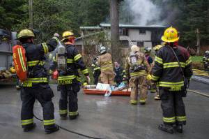 Capital City Fire/Rescue personnel respond to a house fire at 19140 Randall Road on Friday, May 11, 2018. According to Chuck Collins the house was recently bought by his daughter, Brooke, and her husband, Kevin Walker. Collins said the fire started in the attached apartment. (Michael Penn | Juneau Empire)
