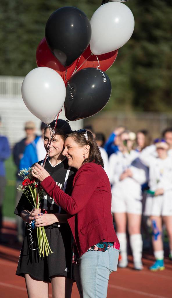 Juneau-Douglas&rsquo; Leah Bibb receives balloons from her mother, Mona, for Senior Night at Adair-Kennedy Memorial Park on Tuesday, May 15, 2018. (Michael Penn | Juneau Empire)
