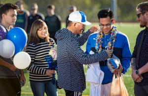 Thunder Mountain&rsquo;s Phillip Escorrido accepts gifts from his father, Eddie, mother, Florian and older brother, Patrick, in front of Coach Joshua Odum, right, for Senior Night at TMHS on Wednesday, May 16, 2018. (Michael Penn | Juneau Empire)