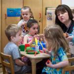 Director Gretchen Boone works with preschool children in their play kitchen at Gold Creek Child Development Center on Thursday, May 24, 2018. (Michael Penn | Juneau Empire)