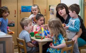 Director Gretchen Boone works with preschool children in their play kitchen at Gold Creek Child Development Center on Thursday, May 24, 2018. (Michael Penn | Juneau Empire)