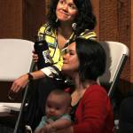 Sisters Ursala Hudson (top) and Lily Hope watch part of a presentation they led entitled &ldquo;Listening to our Teachers: Bringing History to the Present in Chilkat and Ravenstail Weaving&rdquo; inside the Walter Soboleff Building&rsquo;s clan house on Wednesday, June 6, 2018. Hope holds her 8-month-old daughter Anastasia. (Alex McCarthy | Juneau Empire)