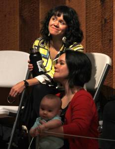 Sisters Ursala Hudson (top) and Lily Hope watch part of a presentation they led entitled &ldquo;Listening to our Teachers: Bringing History to the Present in Chilkat and Ravenstail Weaving&rdquo; inside the Walter Soboleff Building&rsquo;s clan house on Wednesday, June 6, 2018. Hope holds her 8-month-old daughter Anastasia. (Alex McCarthy | Juneau Empire)