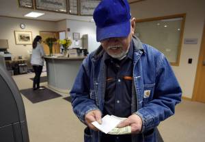 Nestor Endozo looks at his change after paying his electric bill at Alaska Electric Light and Power on Monday, June 11, 2018. (Michael Penn | Juneau Empire)