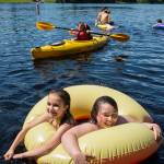 Jaden Capua-Flores, left, and Piper Robidoux, both 13, share a float as they cool off with other children at Auke Lake on Tuesday, June 19, 2018. (Michael Penn | Juneau Empire)