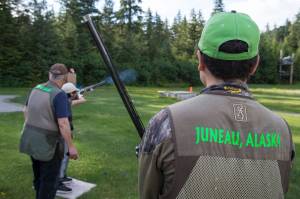 Brice Norton, right, waits his turn as Coach Mark Kappler watches Mackenzie Lam practice trap shooting at the Juneau Gun Club on Thursday. (Michael Penn | Juneau Empire)