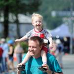 Myron Davis carries his son during the start of the Glenn Frick Memorial Mile, which took place just before the start of the Juneau Fourth of July Parade on Wednesday. (Nolin Ainsworth | Juneau Empire)
