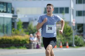 Zach Bursell sprints to the finish line of the Glenn Frick Memorial Mile, which took place just before the start of the Juneau Fourth of July Parade on Wednesday morning. Bursell placed first overall and set a new course record in the mile. (Nolin Ainsworth | Juneau Empire)