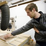 Max Stanley, of Latitude Woodwares, shows off a home-made Computer Numeric Contro machine at their Auke Bay shop on Thursday. The machine can use both a router and laser to engrave wood panels. (Michael Penn | Juneau Empire)