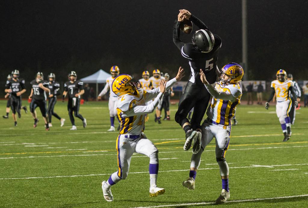 Juneau Uniteds Hansel Hinckle is kept from completing a reception on the goal line by Lathrops Michael Zadra, left, and Bubba Maschmeier at Thunder Mountain High School on Saturday. (Michael Penn | Juneau Empire)