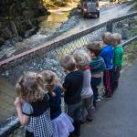 Children attending Fiddleheads Preschool line up along the fence at Cope Park to watch an excavator dredge Gold Creek on Wednesday, Sept. 12, 2018. (Michael Penn | Juneau Empire)