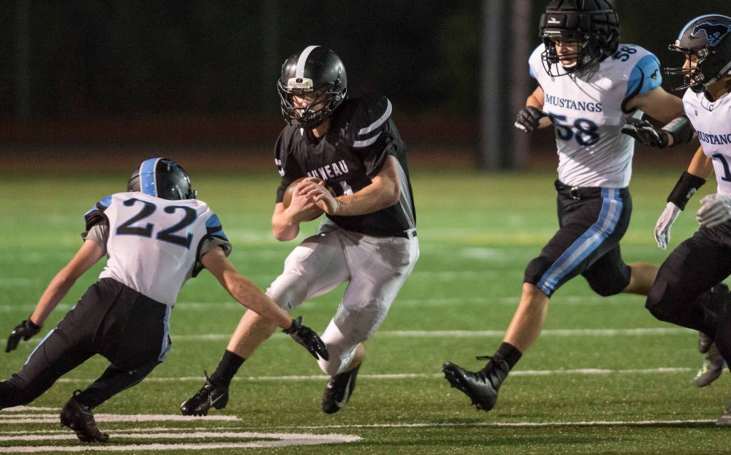 Juneau Uniteds Caleb Traxler finds himself surround by Chugiaks James Mathes, left, Torrin Girard and Brandon OFihelly at Adair-Kennedy Memorial Field on Friday, Sept. 14, 2018. Chugiak won 22-7. (Michael Penn | Juneau Empire)