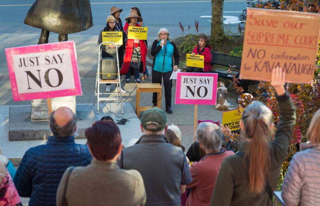 Juneau residents listen to Kate Troll as they participate in a protest against President Donald Trumps nominee to the Supreme Court, Brett Kavanaugh, at Dimond Courthouse Plaza on Tuesday, Sept. 18, 2018. (Michael Penn | Juneau Empire)