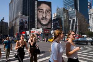 In this Sept. 6, 2018, file photo, people in New York walk past a Nike advertisement featuring former San Francisco 49ers quarterback Colin Kaepernick, known for kneeling during the national anthem to protest police brutality and racial inequality. In response to Nikes support of Kaepernick, the Rhode Island town of North Smithfield is considering asking its departments to refrain from purchasing Nike products. (AP File Photo | Mark Lennihan)