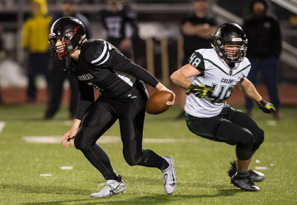 Juneau Uniteds quarterback Cooper Kriegmont, left, evades the rush of Colonys Isaac Richardson at Thunder Mountain High School on Friday, Sept. 21, 2018. (Michael Penn | Juneau Empire)