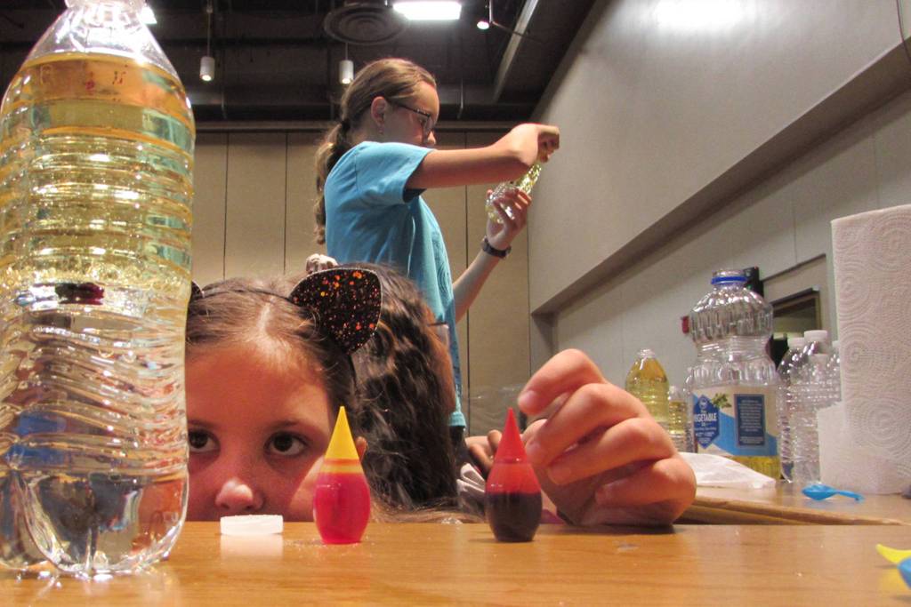 Emma McDowell, 10, peers at a lava lamp she made at one of the Introduce a Girl to Engineering Day stations. The lava lamps were made of water, oil, food coloring and Alka-Seltzer tablets. Girls learned about hydrophobic and hydrophilic liquids. (Ben Hohenstatt | Capital City Weekly)