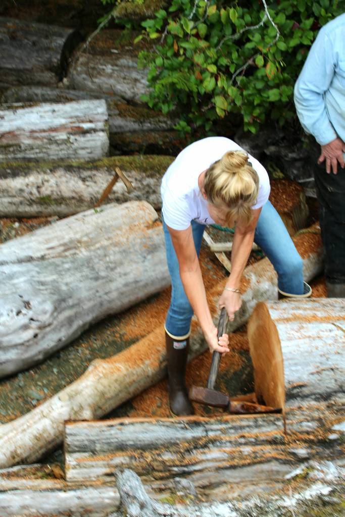 Megan Duncanson swings a sledgehammer against a wedge to split off a piece of shake bolt from a red cedar log. (Tara Neilson | For the Capital City Weekly)