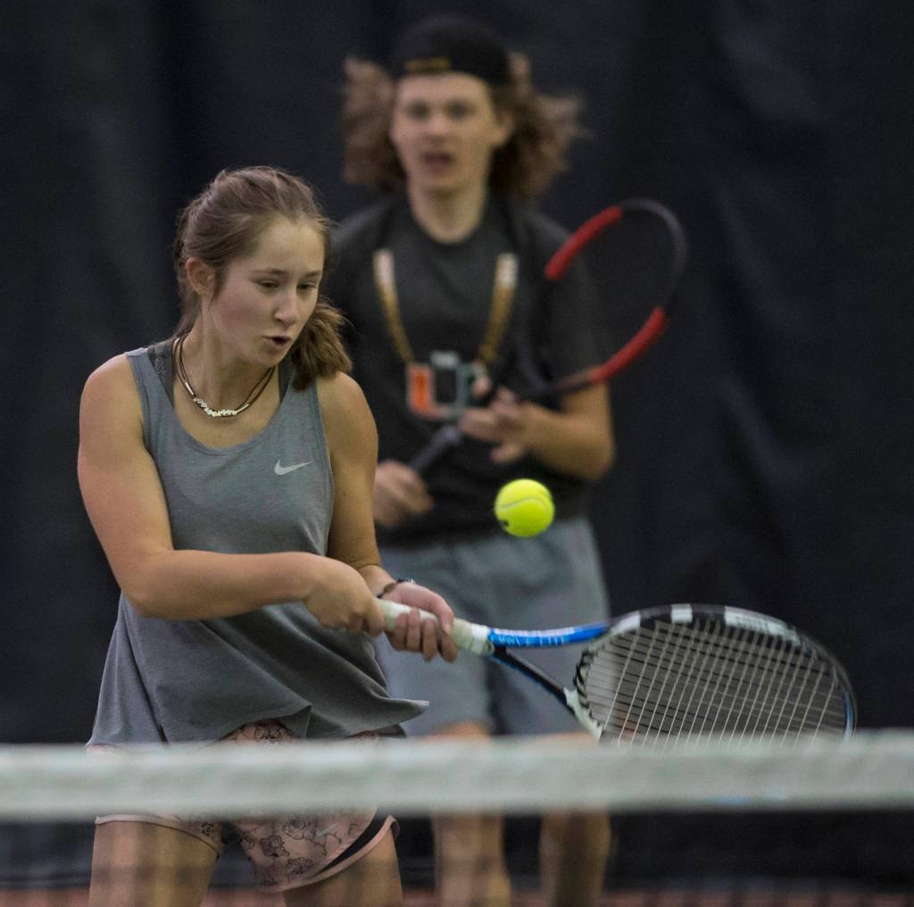 Adelie McMillan volleys a ball against the team of Olivia Moore and River Reyes-Boyles during the Regional Tennis Championships at the JRC/The Alaska Club on Saturday, Sept. 22, 2018. McMillian is backed up by her partner Wolf Dostal in the mixed doubles match. (Michael Penn | Juneau Empire)