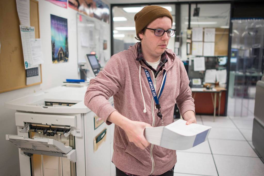 Mainframe Operator Will Muldoon lifts 500 freshly printed Permanent Fund Dividend checks from the printer at the states secure printing facility in Juneau on Tuesday, Sept. 25, 2018. (Michael Penn | Juneau Empire)