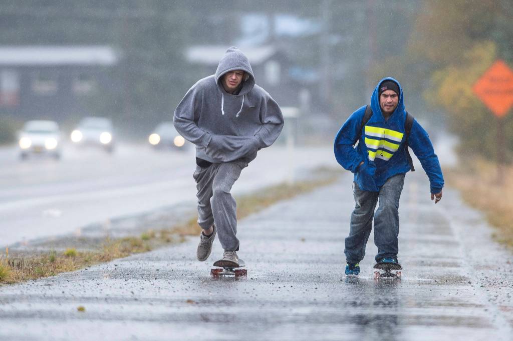 Domanic Quick, left, and Ben Kinser travel by skateboard through the rain along Egan Drive on Tuesday, Sept. 25, 2018. The National Weather Service is calling for periods of rain on Wednesday with a high near 55. (Michael Penn | Juneau Empire)