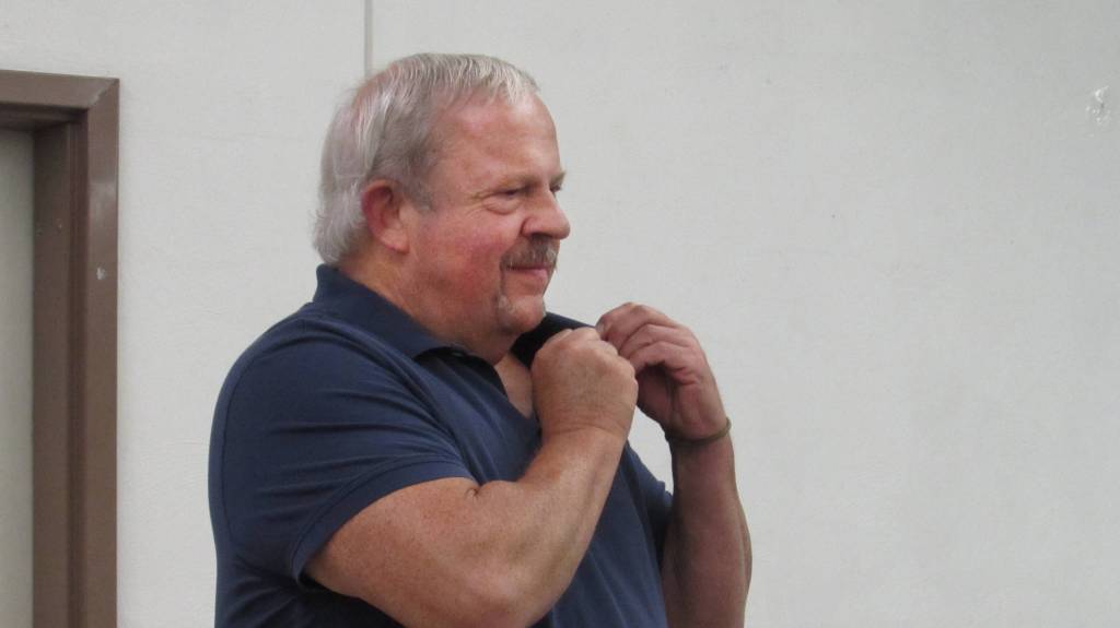 Chip Wisner puts his Competent Communicator pin on his shirt collar. (Ben Hohenstatt | Capital City Weekly)