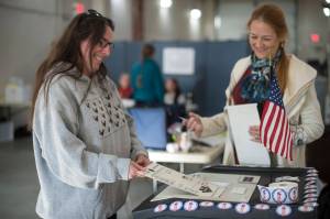LIsa Ryals, left, enters her ballot into a vote counting machine at election official Renee Hughes watches in the Municipal Election at AEL&P on Tuesday, Oct. 2, 2018. (Michael Penn | Juneau Empire)