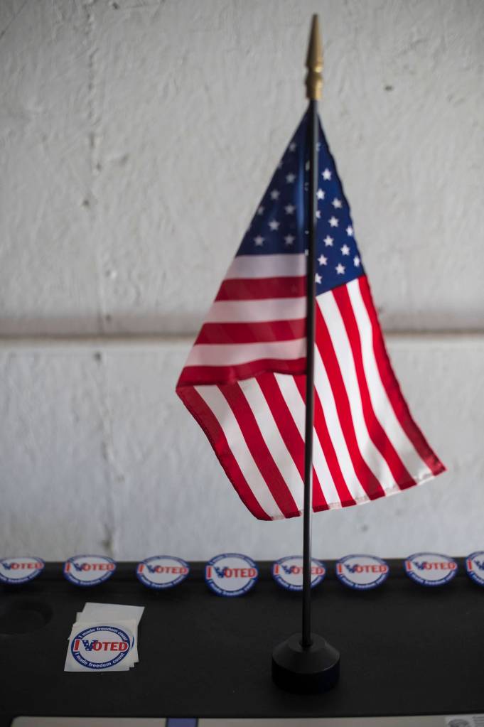 A flag and voting stickers decorate a voting machine for the Municipal Election at AEL&P on Tuesday, Oct. 2, 2018. (Michael Penn | Juneau Empire)