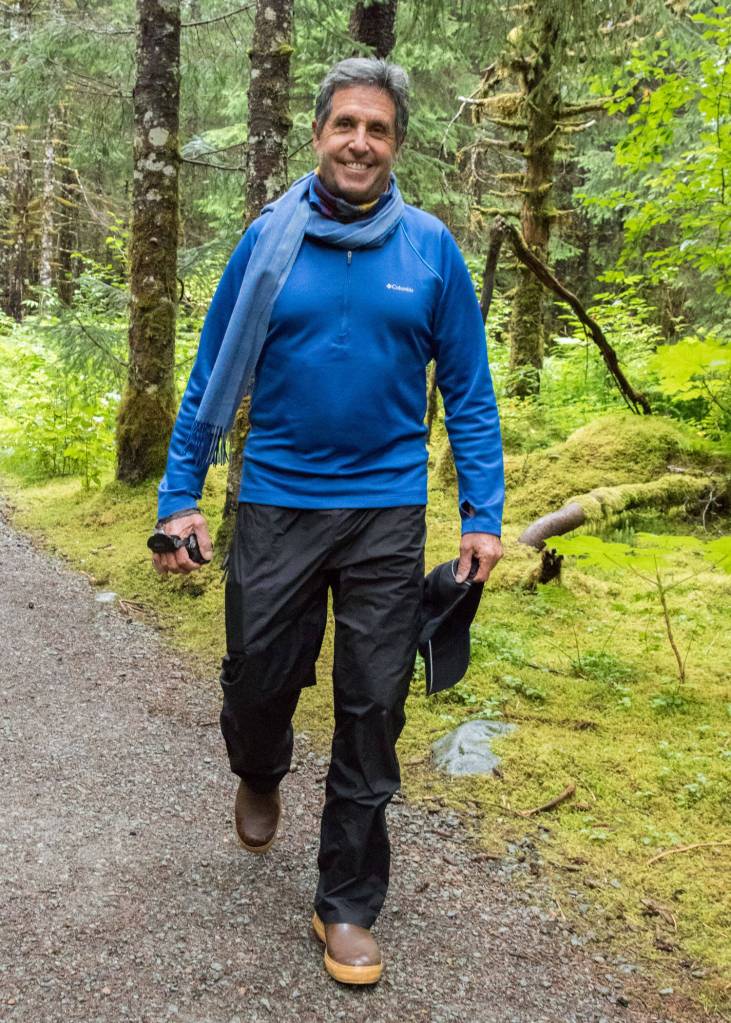 Oct. 21, 2018 Dirk Younkerman loves Alaska and has regularly visited and seasonally worked here since 1993. I ran into him on the trail on a rainy day where he was out enjoying the temperate rainforest. His practical clothes also looked smarta royal blue Columbia fleece shirt, Kathmandu rain pants from New Zealand, Xtratufs, merino wool neck scarf and buff. An avid videographer, his most important accessories are his video camera and his ever-present smile, which reveals how much he enjoys Juneau.