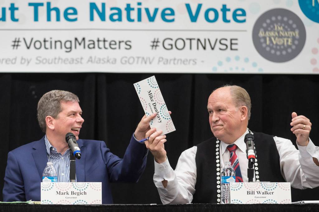 Former U.S. Sen. Mark Begich, left, and Gov. Bill Walker pass Mike Dunleavys name plate during a Special Native Issues Forum for governor candidates at the Elizabeth Peratrovich Hall on Tuesday, Oct. 2, 2018. Libertarian candidate Billy Toien, out of picture to the left, requested the name plate. Dunleavy did not attend the forum. (Michael Penn | Juneau Empire)