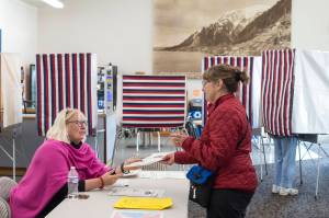 Election official Jacqueline Fowler, left, hands Becky Dierking her ballot in the Municipal Election at the Auke Bay Ferry Terminal on Tuesday, Oct. 2, 2018. (Michael Penn | Juneau Empire)