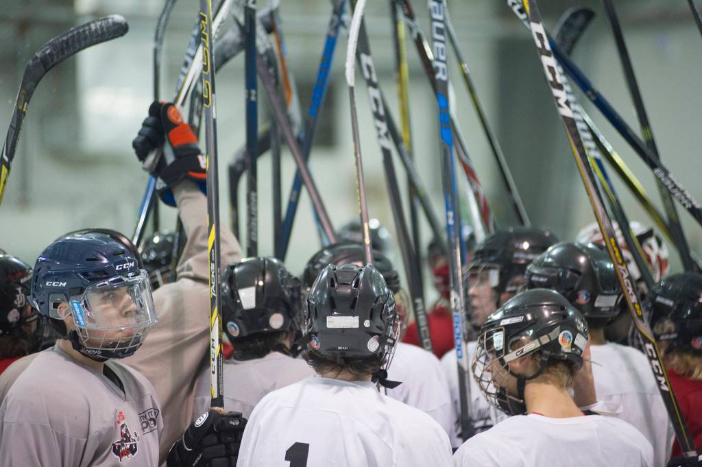 The Juneau-Douglas High School hockey team raises its sticks for a cheer at the end of its first practice of the season on Wednesday morning at Treadwell Arena. (Nolin Ainsworth | Juneau Empire)