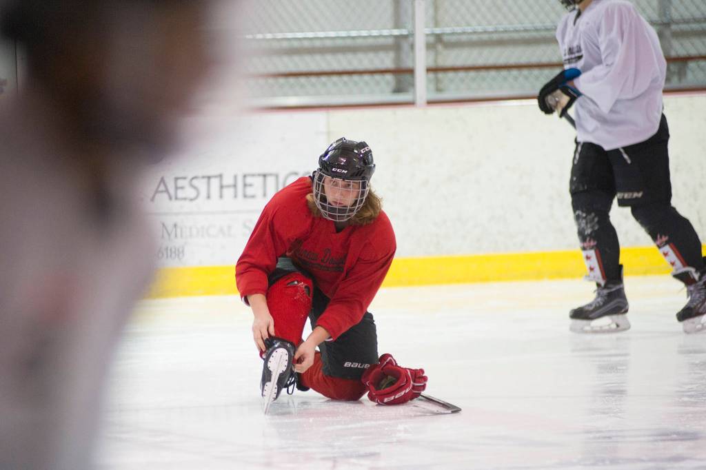 Juneau-Douglas High School senior Logan Ginter adjusts his skates during warmups on Wednesday morning at Treadwell Arena. (Nolin Ainsworth | Juneau Empire)
