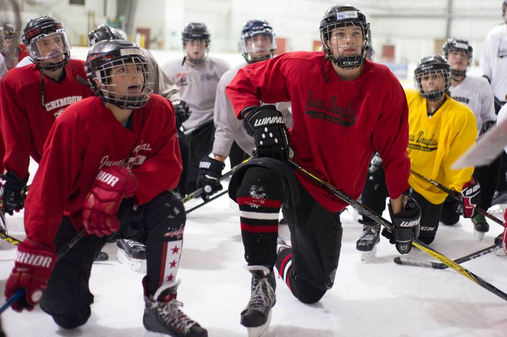 Juneau-Douglas High Schools Joey Meier, left, and Dalton Hoy, right, listen to coach Luke Adams during the teams first practice of the season on Wednesday morning at Treadwell Arena. The teams first home games are Nov. 16-17 against Palmer. (Nolin Ainsworth | Juneau Empire)